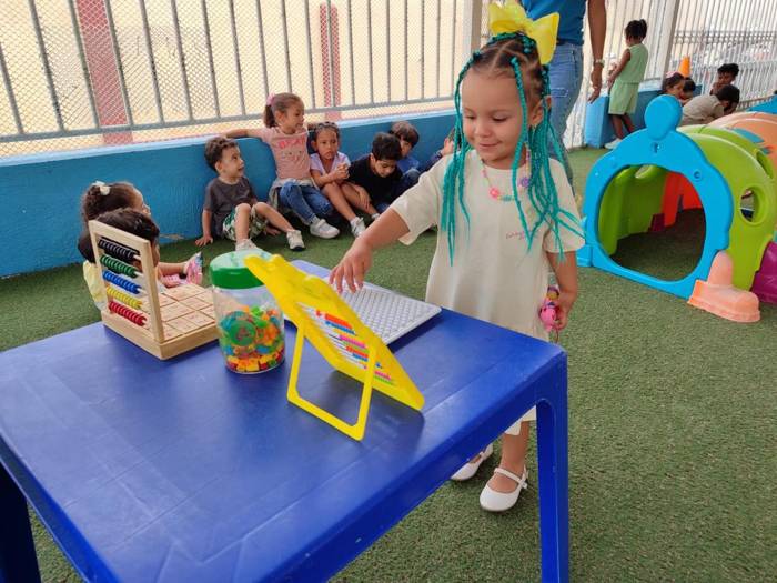 Niña jugando con un ábaco en el Centro de estimulación